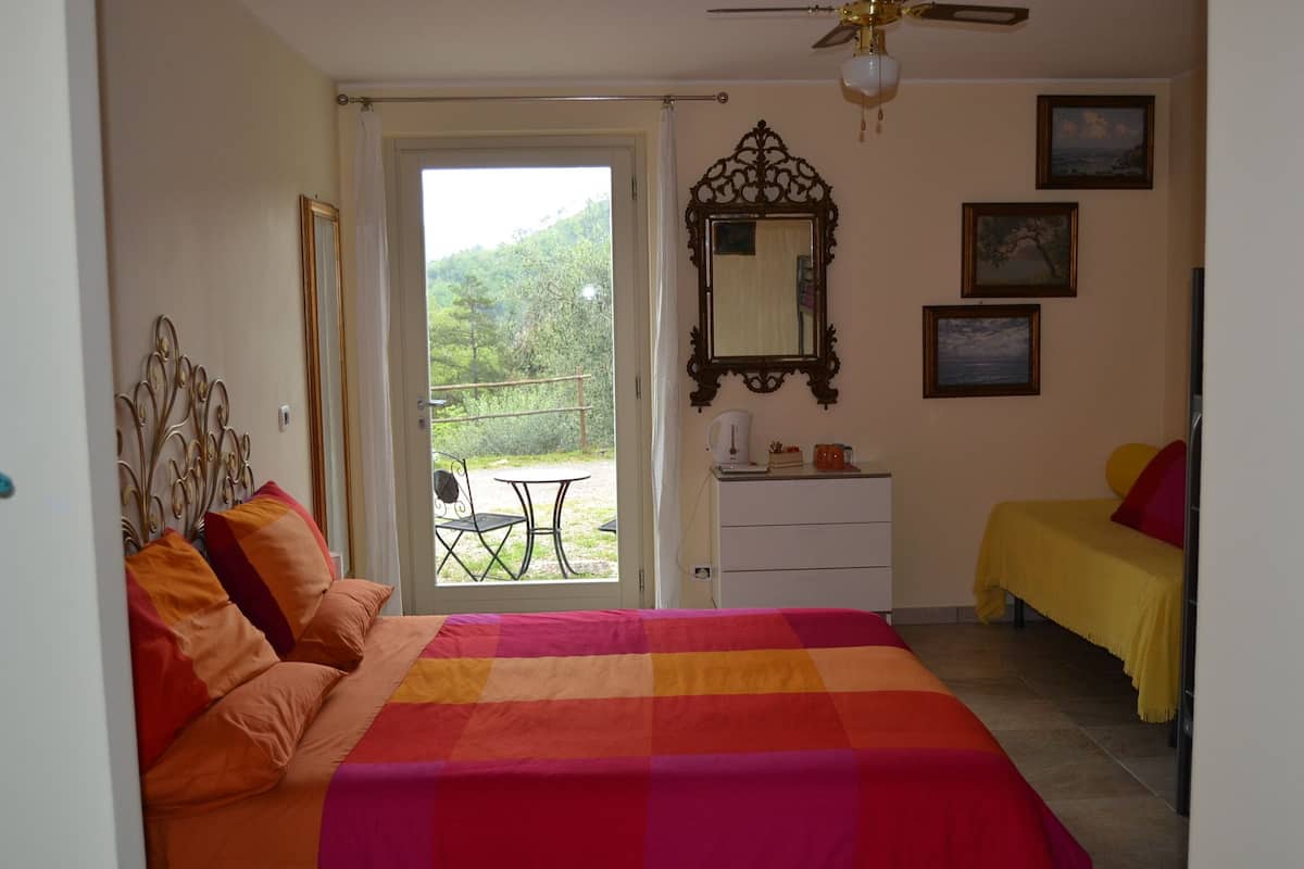 Un dormitorio con cama, escritorio, silla, balcón y ventana.