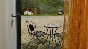 Une porte donnant sur un espace extérieur aménagé avec une table et des chaises, un chemin de gravier et de la verdure en arrière-plan.