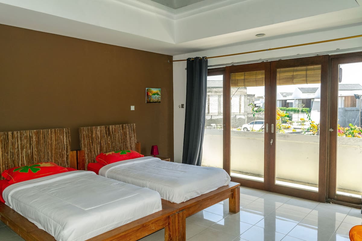 Ein Hotelzimmer mit zwei Betten, einer großen Schiebeglastür nach draußen und einem Gemälde an der Wand.