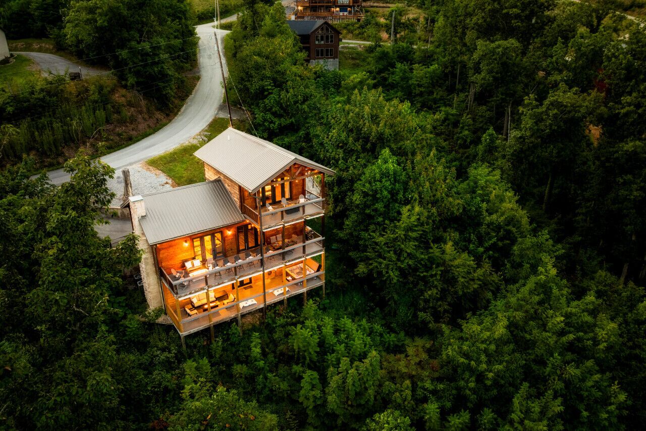 Een tweelaags lodge met een rondom terras, omringd door dicht bos.