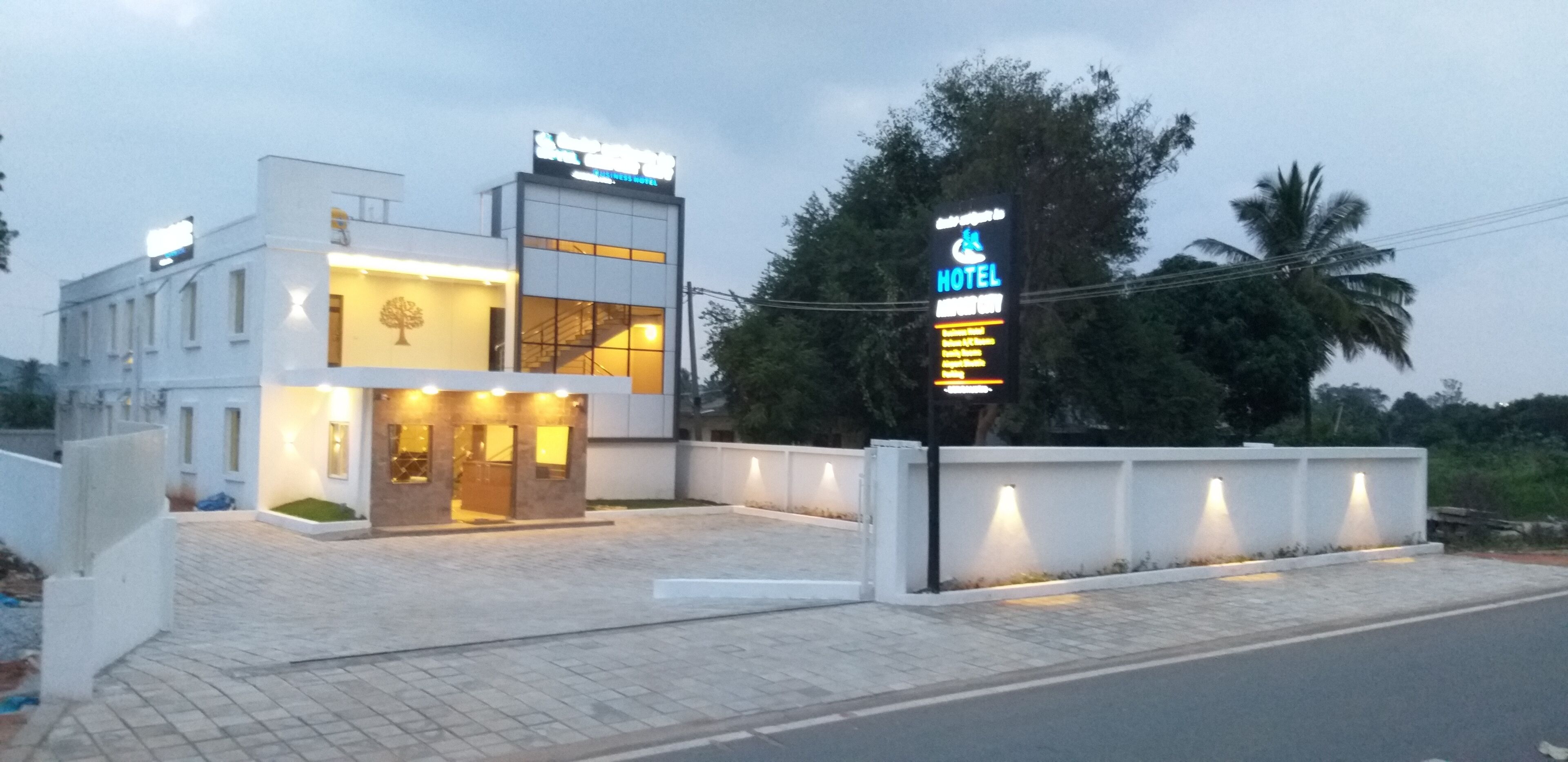 Un hotel moderno con un cartel, una escalera y un área de entrada pavimentada.