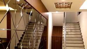 A modern staircase with glass railings and a geometric ceiling design.