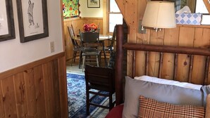 Ein gemütlicher Raum mit Schlafkoje, Holzwänden, einer Essecke mit Tisch und Stühlen sowie einer Treppe zu einer erhöhten Ebene.
