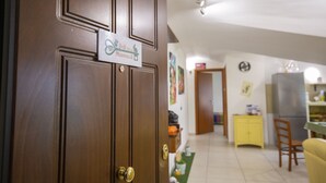 A wooden door with a sign, a kitchen area with a yellow cabinet, and a dining table with chairs. - B&B Delle Meraviglie (Pellezzano)