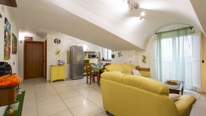 A spacious living area with a yellow sofa, a dining table, and a kitchen in the background. - B&B Delle Meraviglie (Pellezzano)