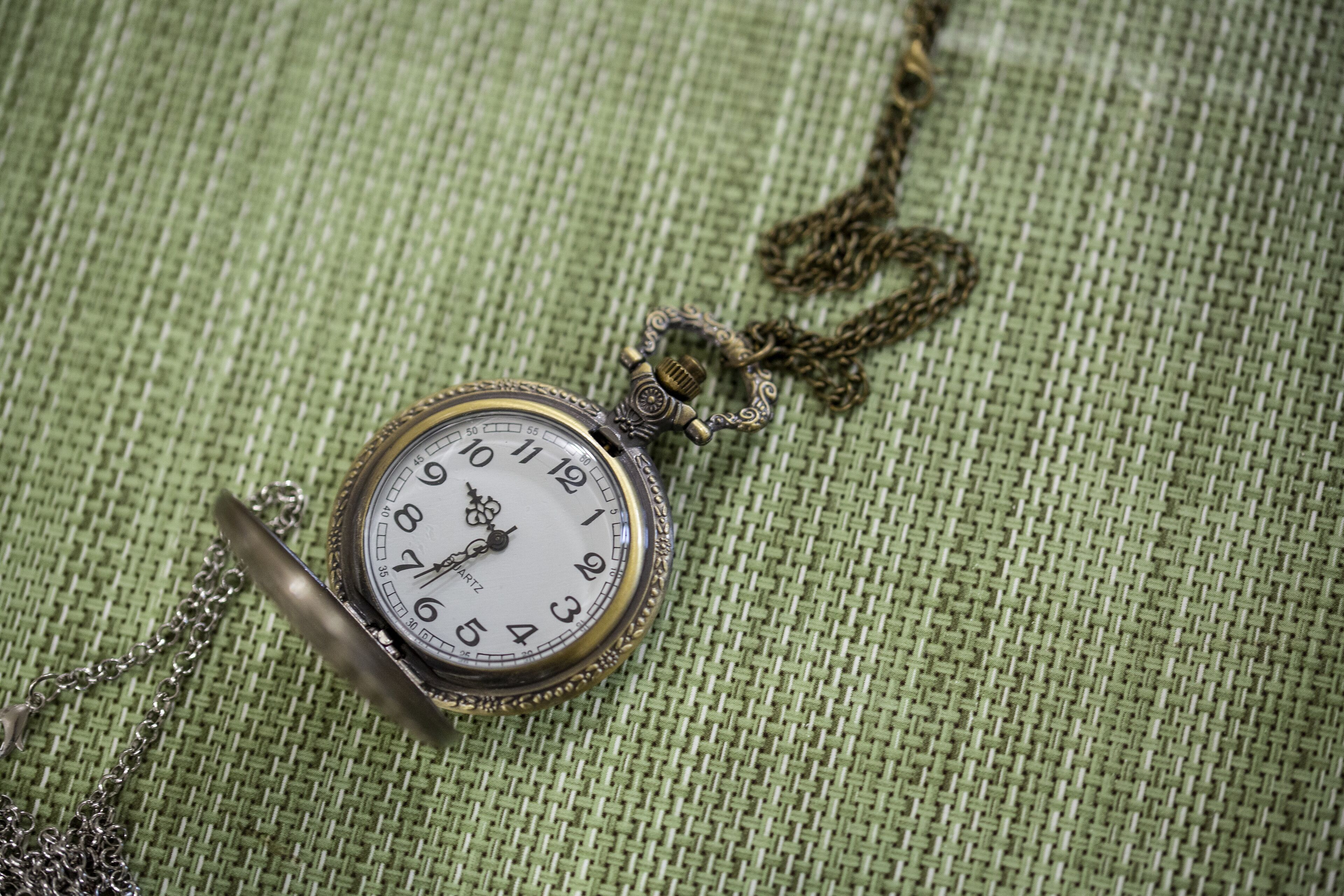 A pocket watch with a chain on a textured fabric background.