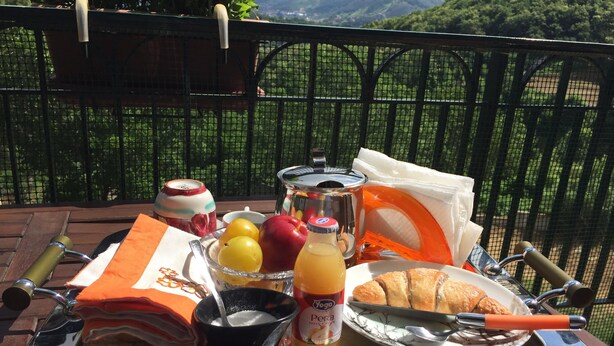 A breakfast tray with fruits, a bottle of juice, a teapot, and a croissant on a table outdoors. - B&B Delle Meraviglie (Pellezzano)