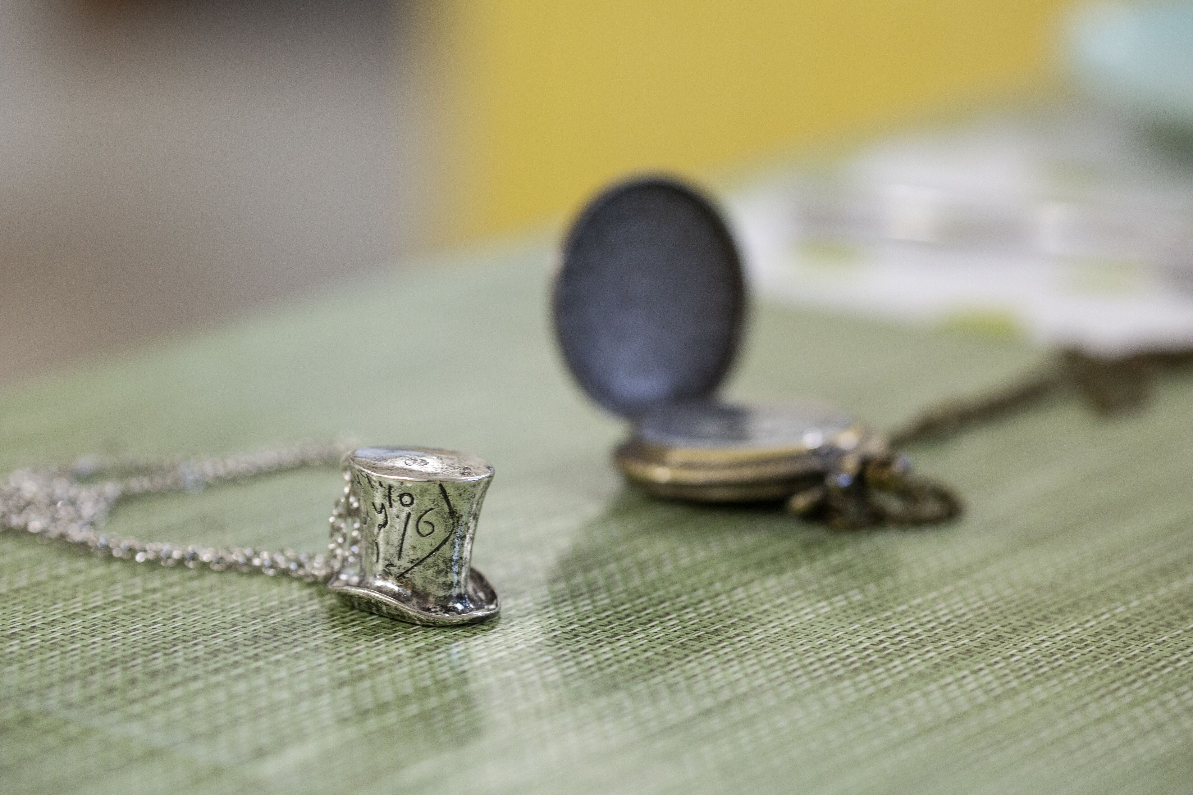 Un collar con un dije y una moneda sobre una superficie de tela verde.