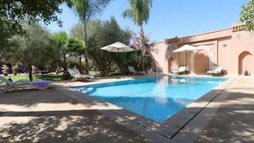 Una piscina al aire libre, sillones reclinables de piscina