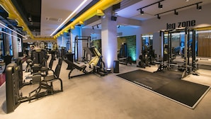 A gym with various exercise equipment, including weight machines and free weights, and a designated leg zone area. - Nov Hotel (Tirana)