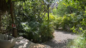 Un jardín con un banco de hormigón, una mesita y un cartel que indica un baño.
