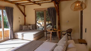 A cozy bedroom with a bed, a small table with fruit, and a view of the outdoors.
