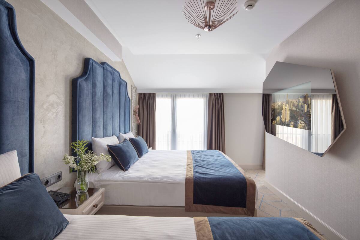 Una habitación de hotel moderna con dos camas, un espejo grande y vistas a la ciudad.