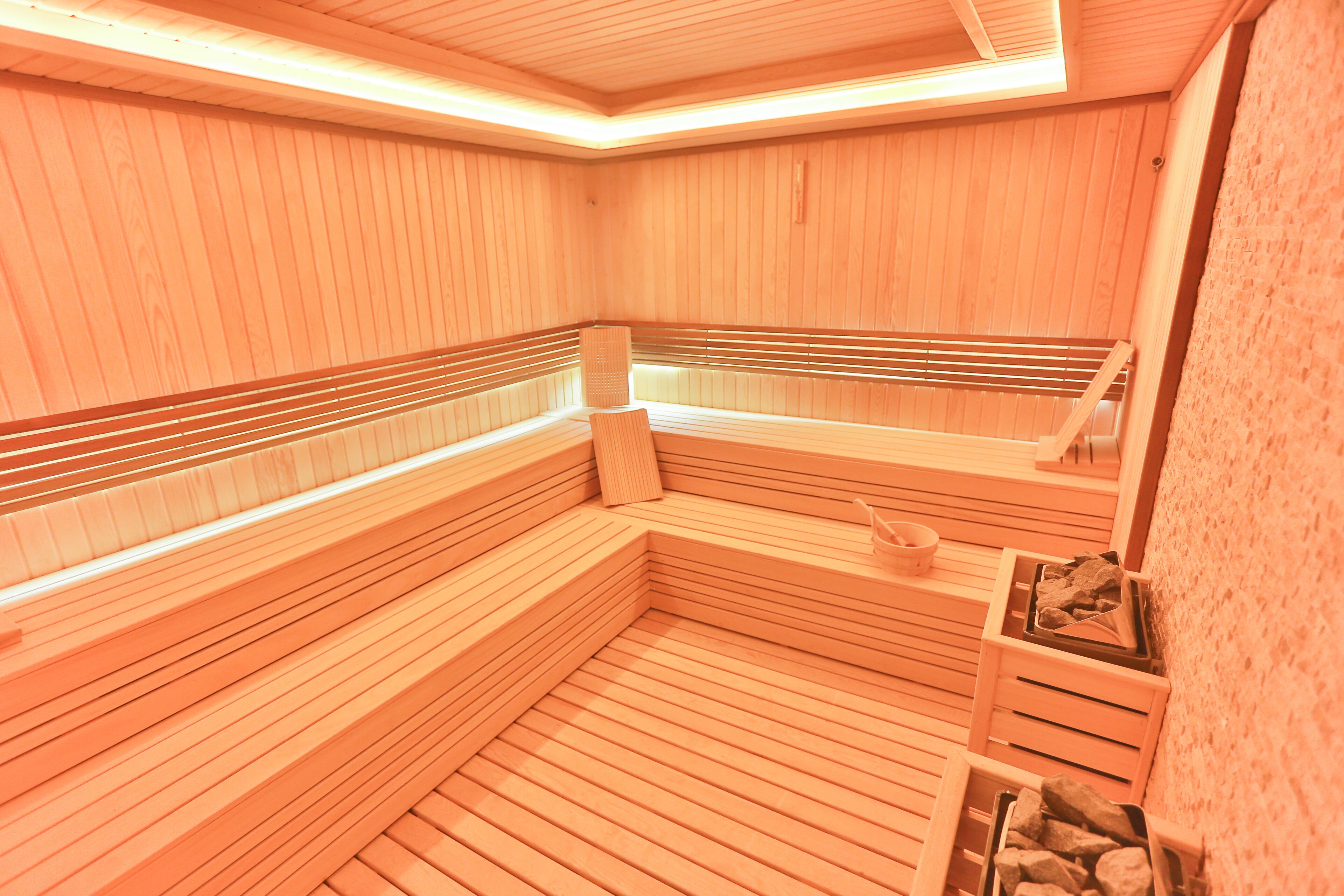 Eine Sauna mit Holzbänken, eine Bank mit Handtuch und eine kleine Ablagefläche mit Gegenständen.