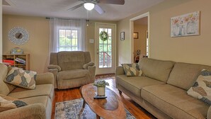 A living room with a ceiling fan, two sofas, a coffee table, and a bookshelf.