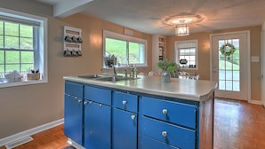 A kitchen with blue cabinets, a large island, and a sign that says "Coffee."