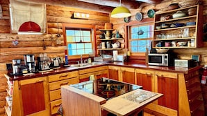 Una cocina rústica con armarios de madera, una isla central y diversos electrodomésticos.