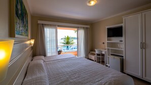 Een hotelkamer met twee bedden, een televisie, een bureau en een balkon met uitzicht op het zwembad.