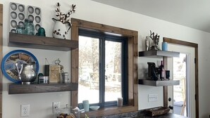 A kitchen with wooden shelves, a window, and a marble countertop.