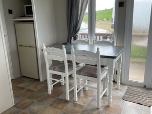 A dining area with a table and chairs, a small refrigerator, and a view of the outdoors. - Farm Stay Property Pets and Families Welcome (Ballyshannon)