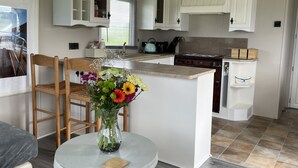 Cocina compacta con muebles blancos, una isla central y un comedor con mesa y sillas.