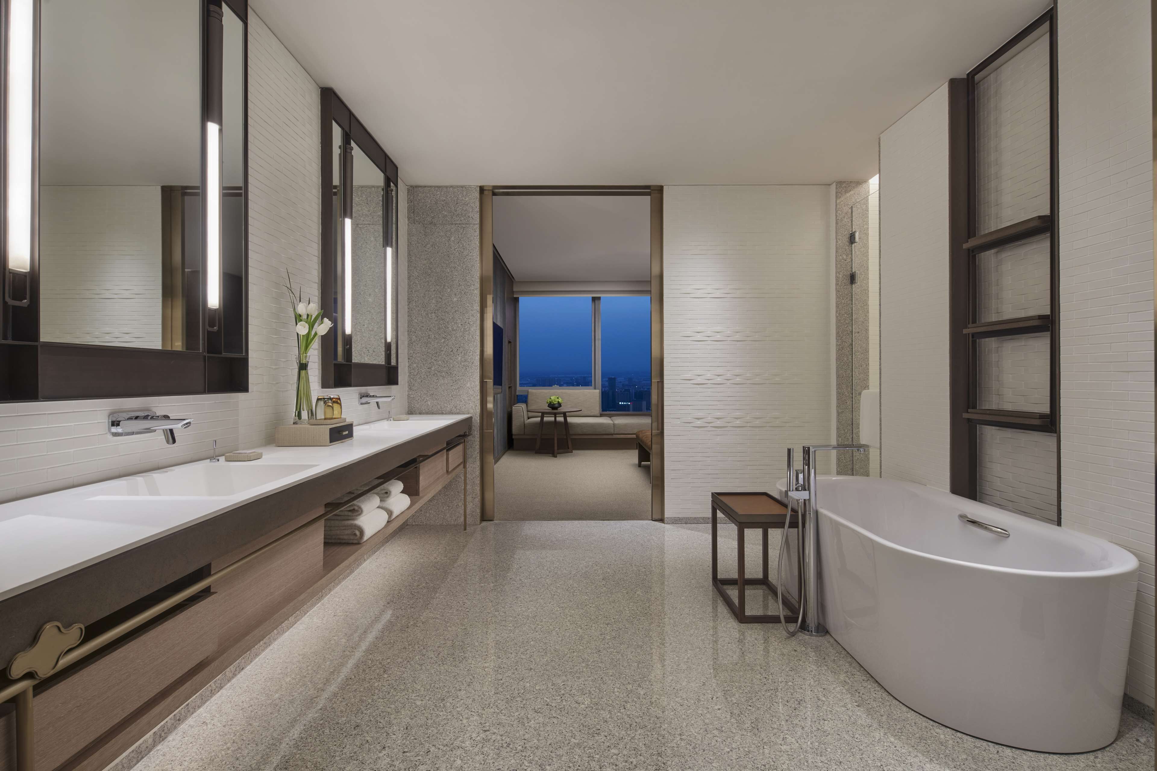 A modern bathroom with a large bathtub, a double sink vanity, and a large mirror.