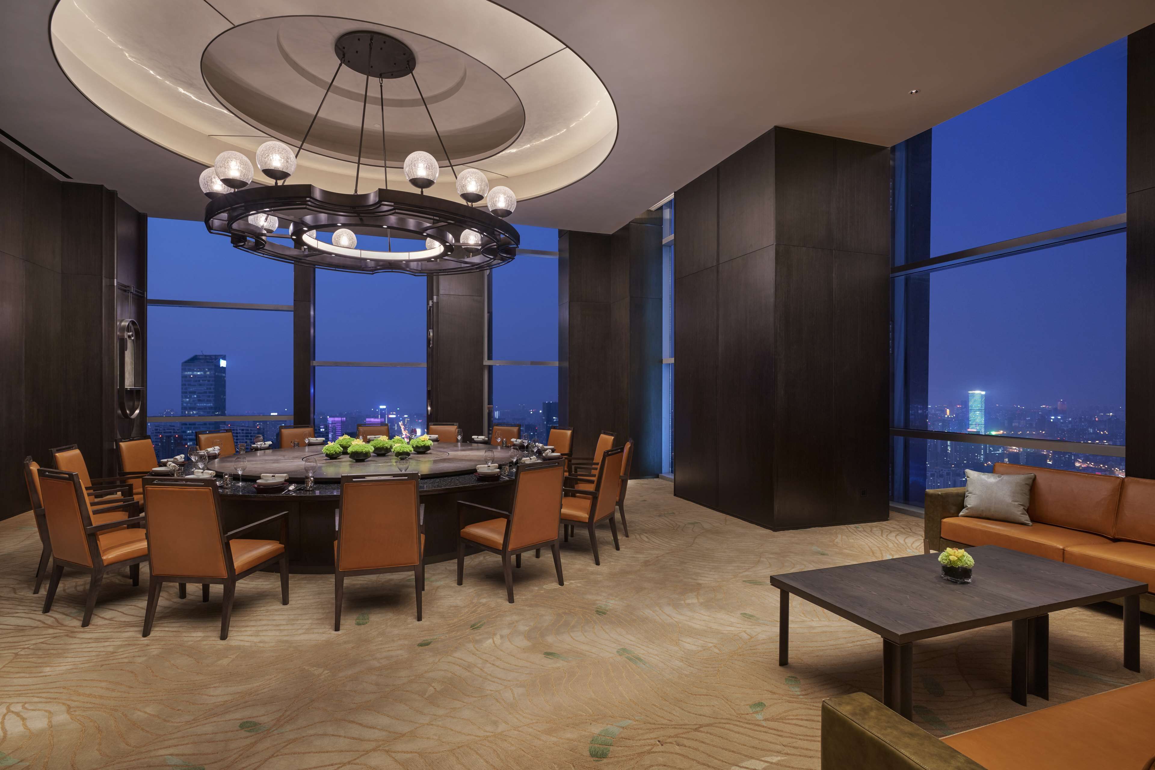 A modern dining area with a round table, chairs, and a chandelier.