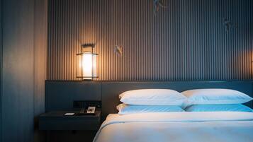Una habitación de hotel con una cama, una mesita de noche con teléfono y una lámpara fijada a la pared.