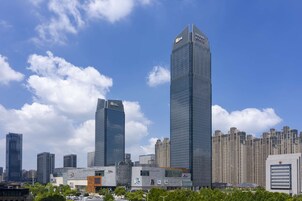 A cityscape with modern skyscrapers, including a prominent tall building with a unique top design.