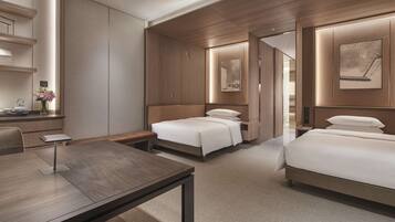 A modern hotel room with a wooden bed, a desk, and a bedside table.