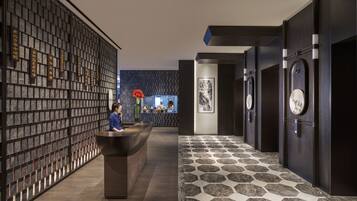 A reception area with a reception desk, a wall with vertical text, a patterned floor, and a wall-mounted clock.