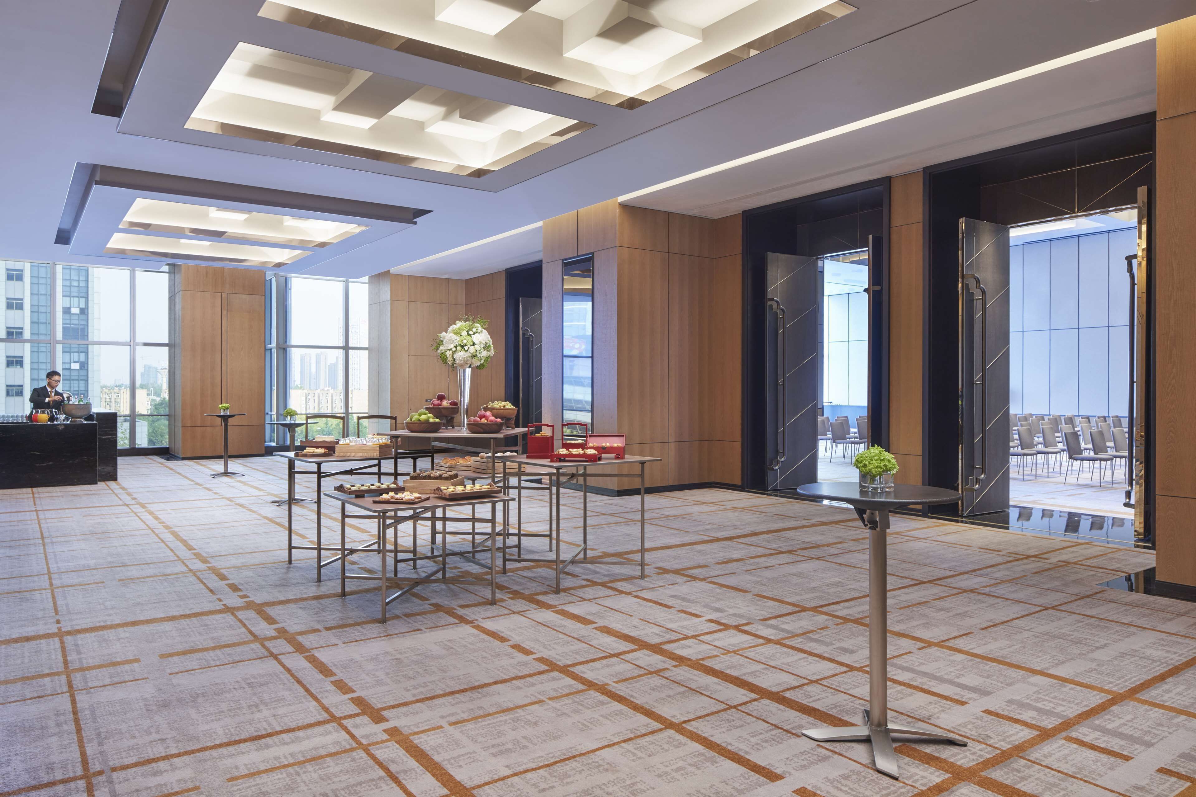 En rummelig lobby med et moderne design, med reception, siddeområde og store vinduer med udsigt over byen.