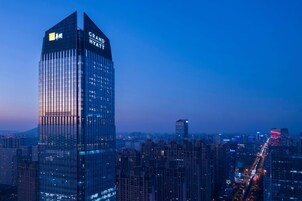 A high-rise hotel with a prominent sign, surrounded by a dense urban skyline and busy streets.