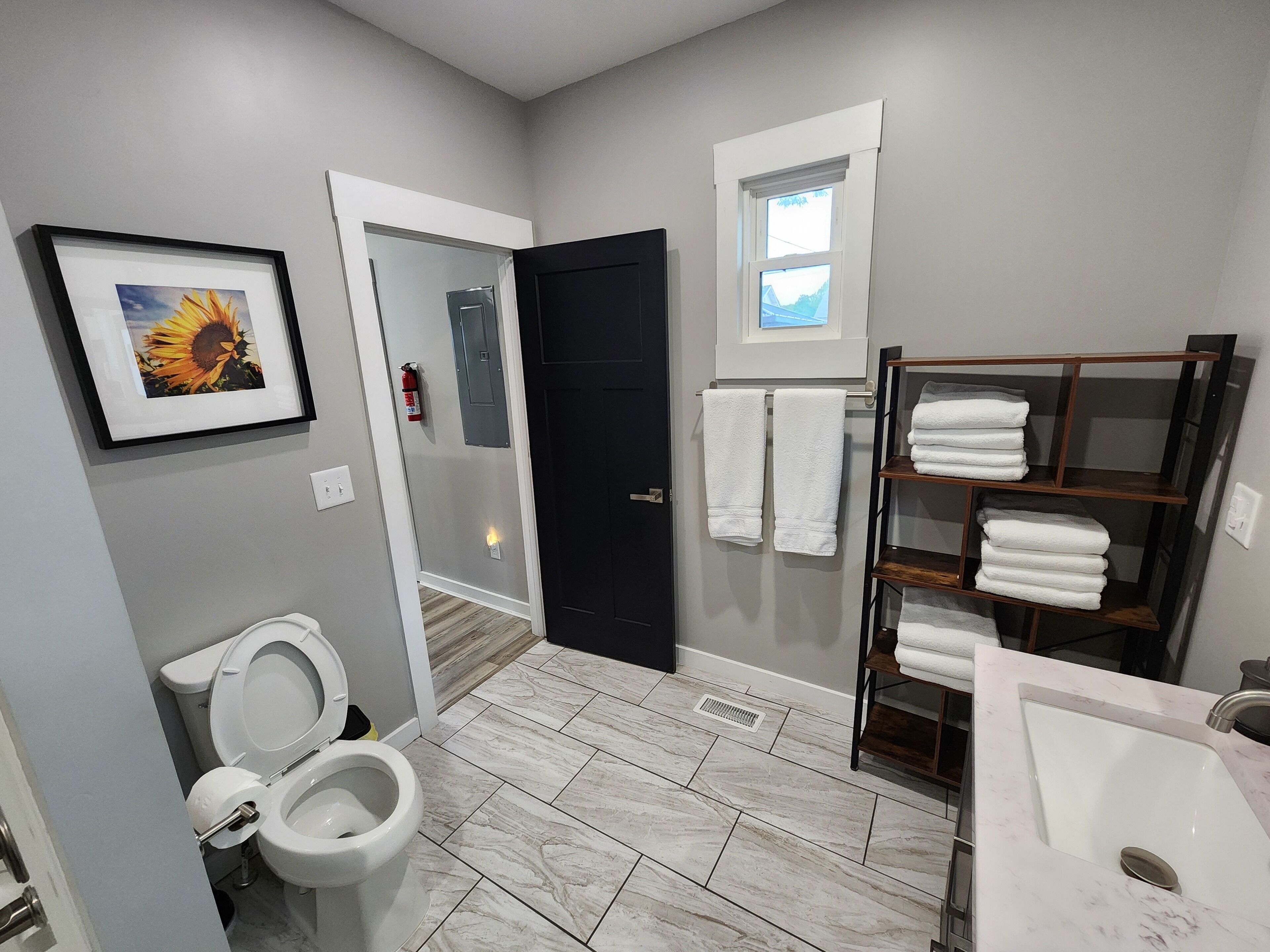 A bathroom with a toilet, sink, and a towel rack with folded towels.