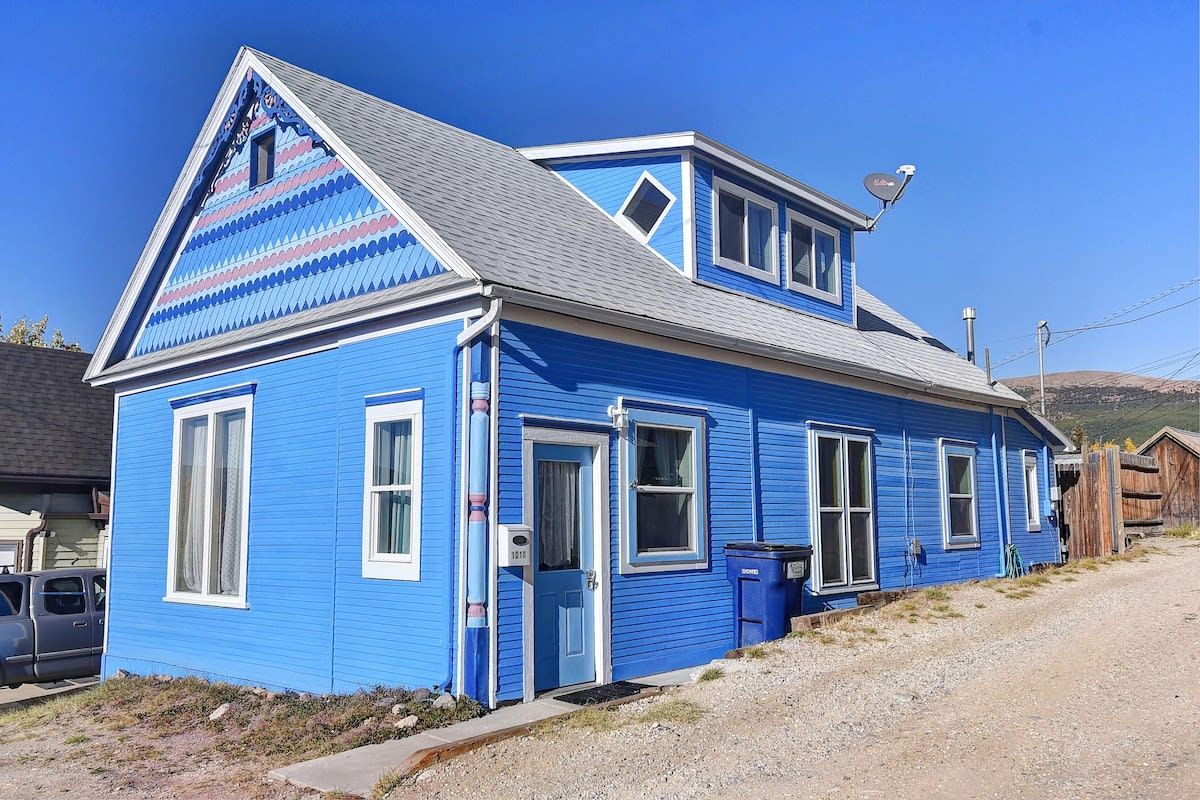 Ein blaues Haus mit Satteldach, einer Satellitenschüssel und einer Schotterauffahrt.