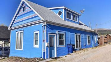Ein blaues Haus mit Satteldach, einer Satellitenschüssel und einer Schotterauffahrt.