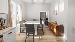 Ein modernes Esszimmer mit großem Tisch und Stühlen, einem Holzschrank und Blick ins Freie.