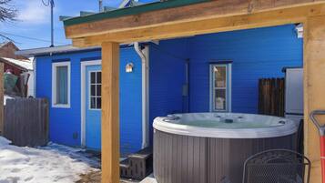 Una casa azul con jacuzzi, terraza de madera y un patio cubierto.