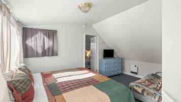 Een slaapkamer met een bed, een dressoir, een televisie en een deur naar een andere kamer.