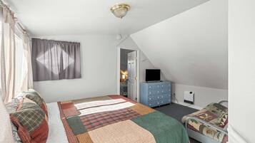 A bedroom with a bed, a dresser, a television, and a door leading to another room.