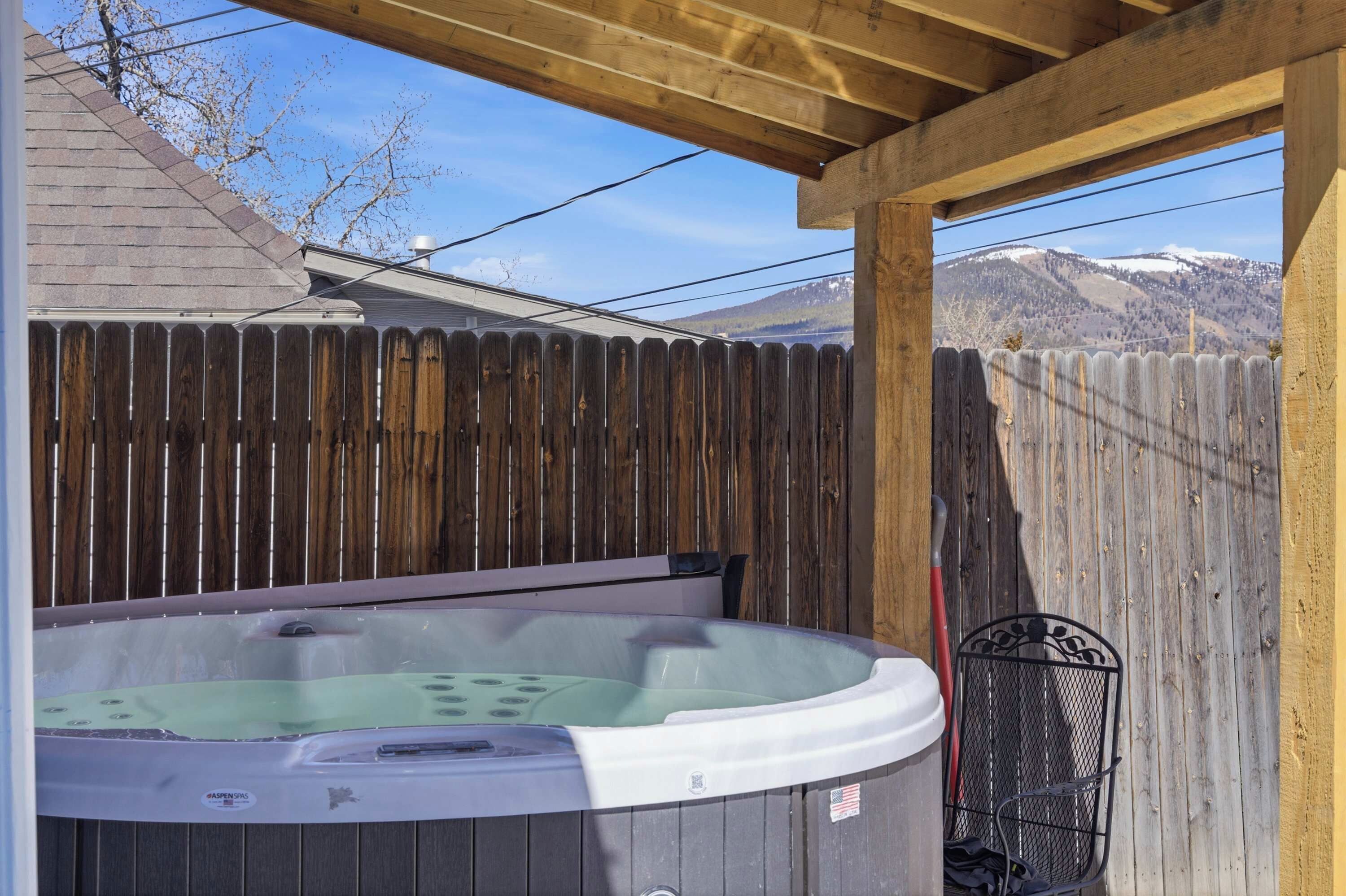 Een hottub onder een houten pergola, met een houten hek op de achtergrond.