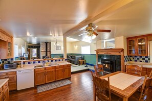 A spacious kitchen with wooden cabinets, a central island, and a dining area with a wooden table and chairs. - Forest Fortress at the Cloud City Castle & Hot Tub (Leadville)