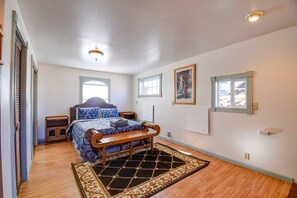 A bedroom with a bed, bedside tables, a window, and a door. - Forest Fortress at the Cloud City Castle & Hot Tub (Leadville)