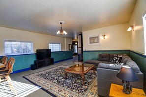 A living room with a television, sofa, coffee table, and patterned rug. - Forest Fortress at the Cloud City Castle & Hot Tub (Leadville)