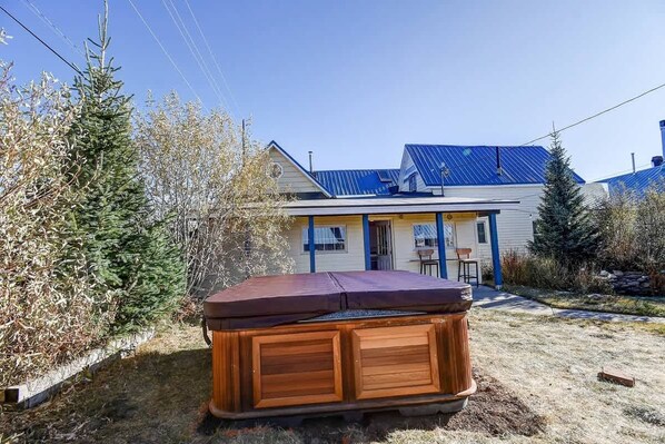 A hot tub in a yard with a house in the background.