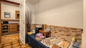 Une pièce comprenant une table à manger dressée, un coin café et un espace cuisine avec des placards et une cuisinière.