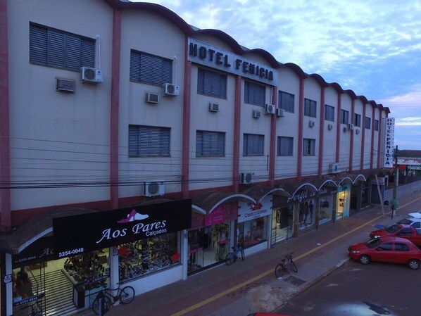 A hotel with multiple units, a storefront with a shoe display, and several parked cars.