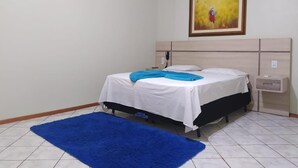 Ein Schlafzimmer mit einem Bett, einem blauen Teppich, einem Bild an der Wand und einem Nachttisch.