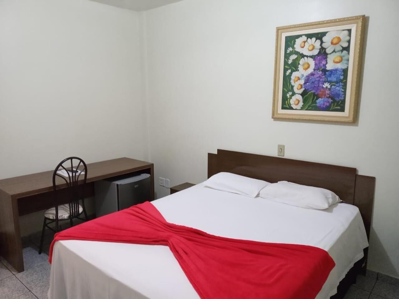 Un dormitorio con cama, escritorio y silla.