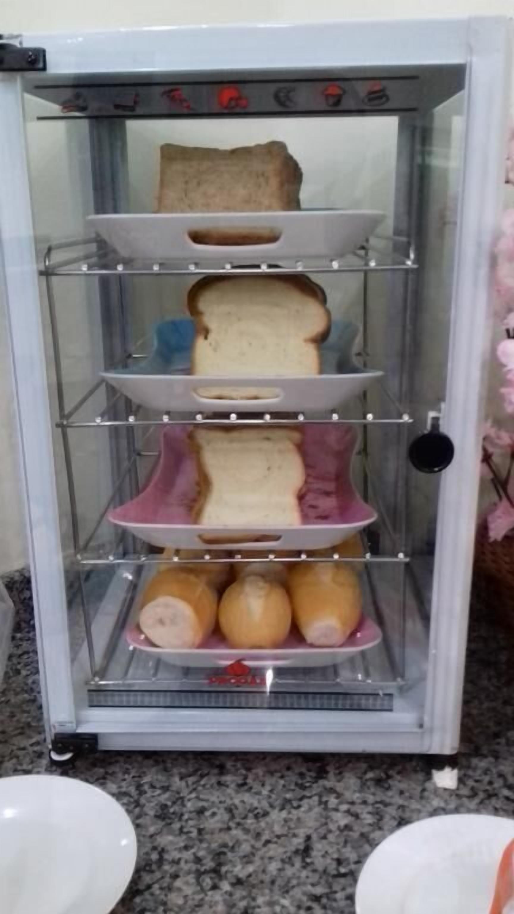 Vitrine de alimentos com várias prateleiras contendo pão e cebolas.
